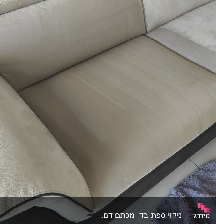 ספה בהירה עם מגבת כחולה על הרצפה